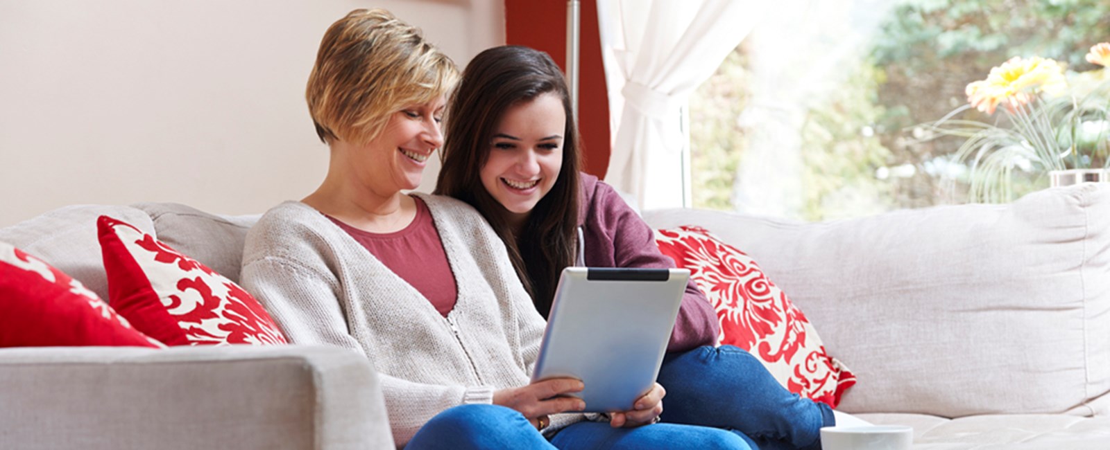 Mother and daughter sitting on a sofa using a tablet